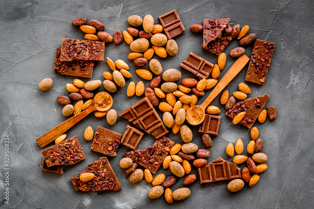 Sweets background with chocolate pieces and nuts on grey stone table top-down Sweets background with chocolate pieces and nuts on grey stone table top-down