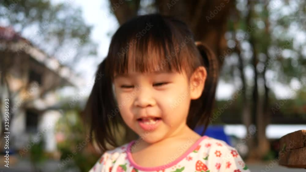 Adorable little girl having fun to eating snack with smile and looking in camera in the public park. Concept of happy family and childhood. Adorable little girl having fun to eating snack with smile and looking in camera in the public park. Concept of happy family and childhood.