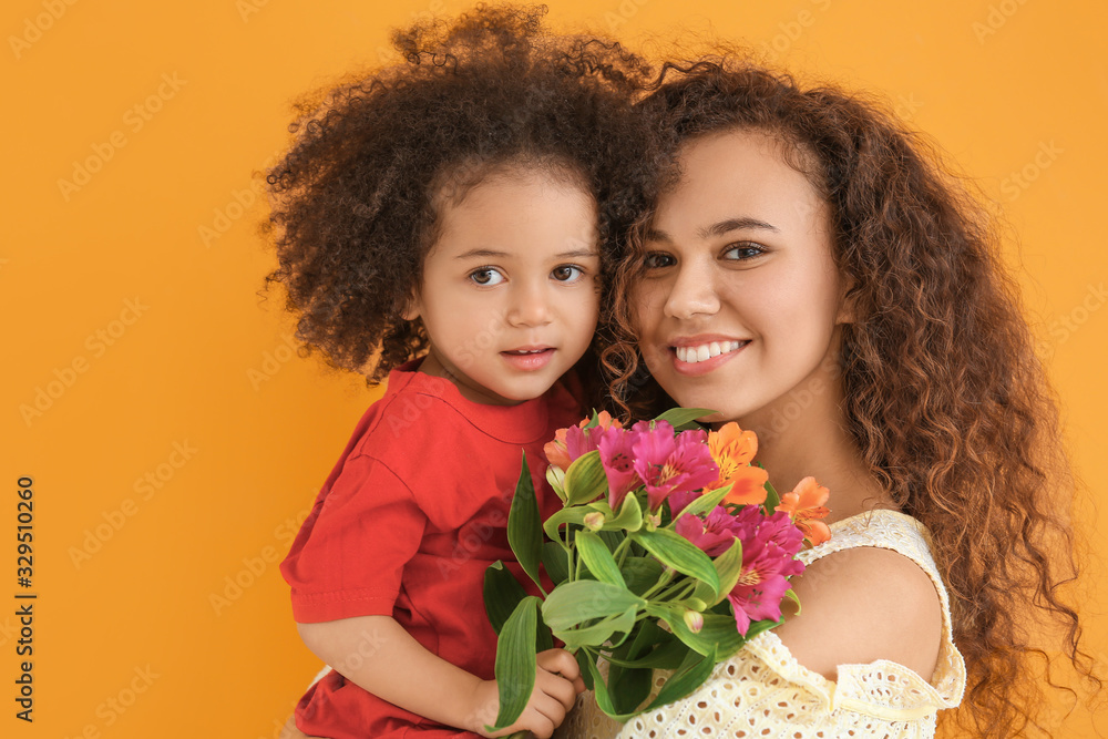 Little African-American girl with her mother and bouquet on color background Little African-American girl with her mother and bouquet on color background