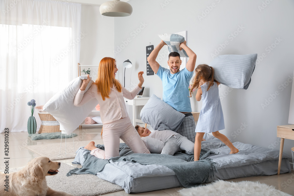 Happy family fighting on pillows in bedroom at home - obrazy, fototapety, plakaty 