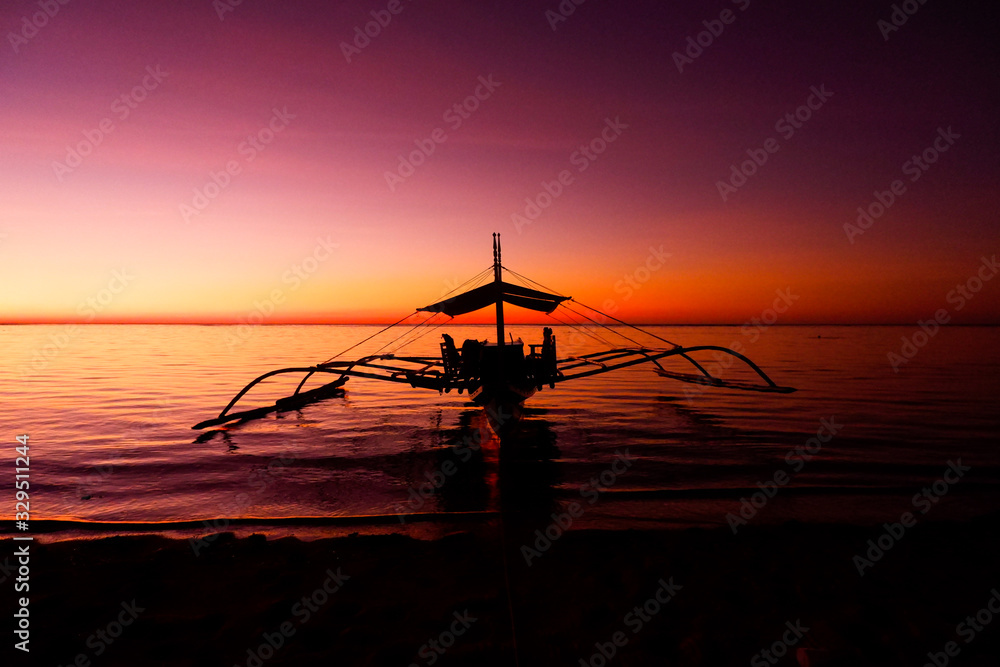 Boat with a reflection in the ocean. Red sunset, Coron island, Philippines.