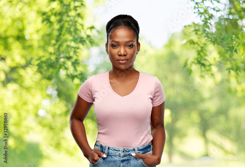 people, ethnicity and portrait concept - african american young woman over green natural background