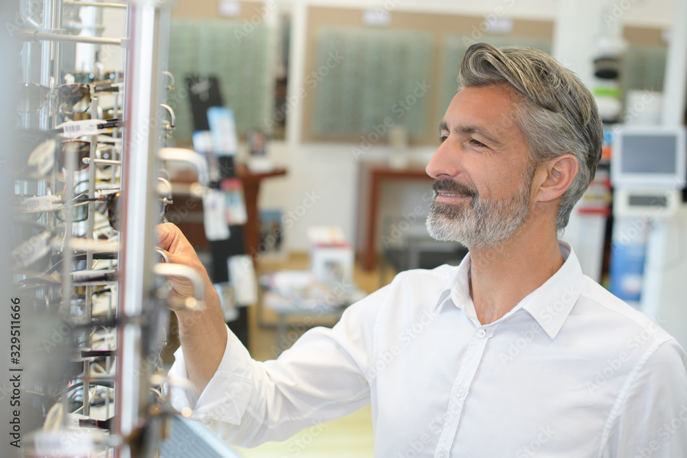 Obraz premium handsome senior man choosing sunglasses in store
