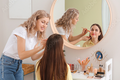 Professional makeup artist working with young woman in salon