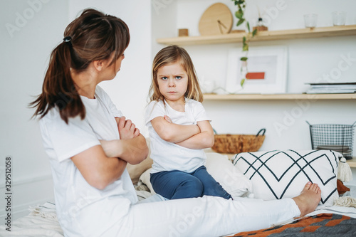 Mother and daughter playing, girl is angry, she lives negative emotions. Family on bed at the bright interior