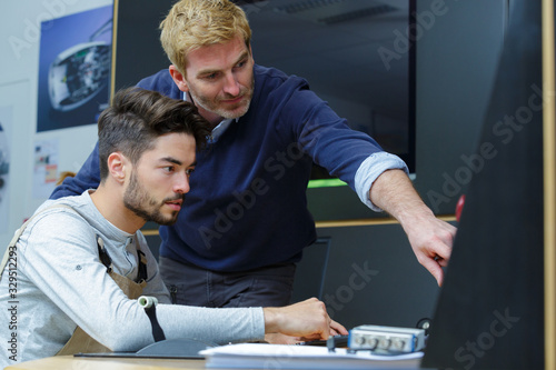 tutor helping student technician using computer photo