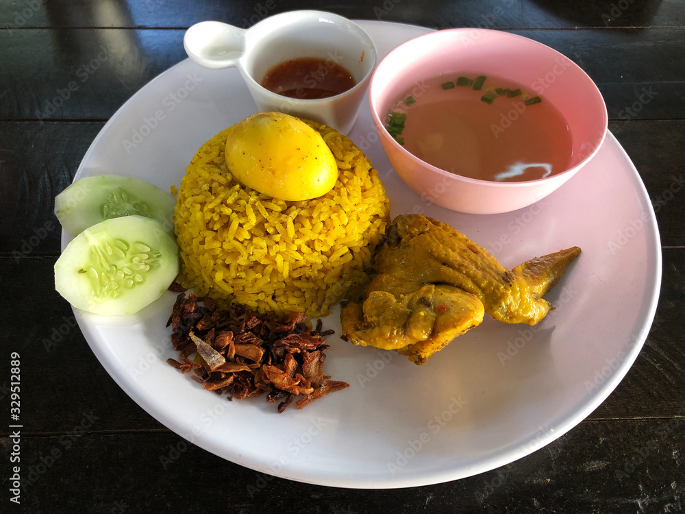 Chicken Biryani. Tradition food of india. Chicken white yellow rice and souce in white plate on the wooden with natural light. This menu in Thailand call 