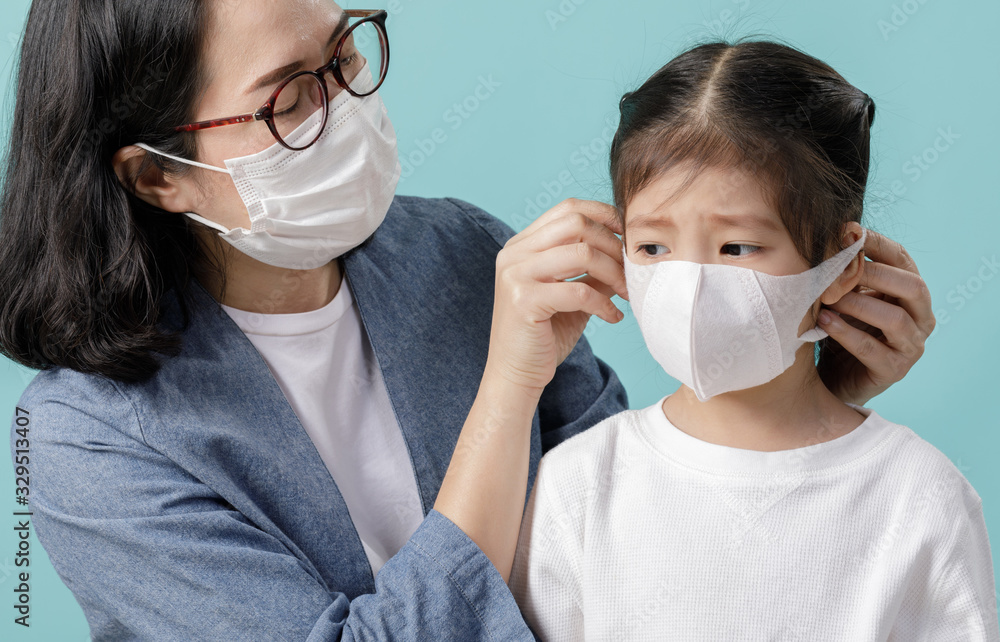 Mom and Asian little child girl is wearing medical face masks to protect themselves from pollution Coronavirus flu virus, New coronavirus 2019-nCoV from China, Empty space isolated on blue background