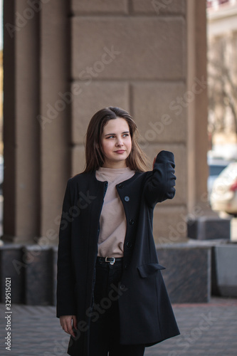 Portrait of a young woman walking around the city and looking around. Beautiful stylish woman walks along the street.