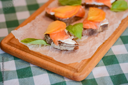 Slamon with mango and cheese sandwiches served on a cutting board over plaid background. photo