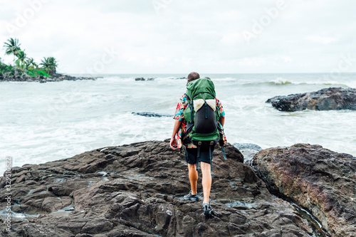 Digital nomad man on the beach with backpack photo