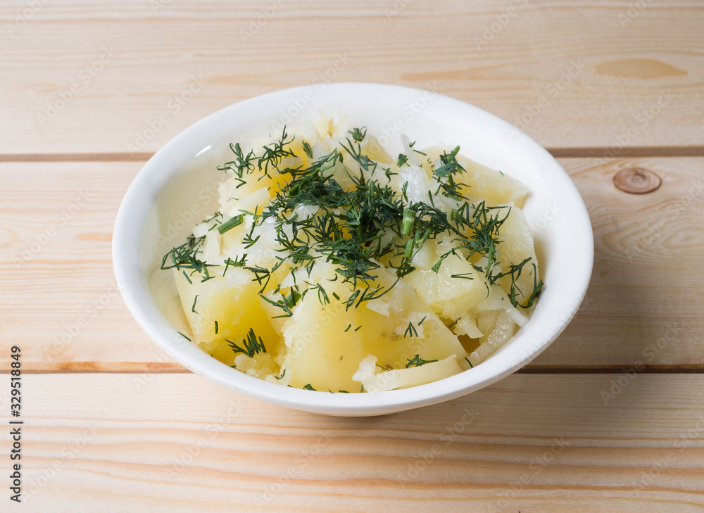 Boiled potatoes with dill in a white bowl on the boards. Side view Boiled potatoes with dill in a white bowl on the boards. Side view