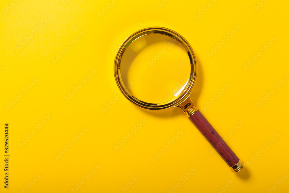 golden magnifier on yellow paper background golden magnifier on yellow paper background
