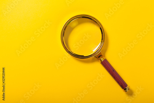 golden magnifier on yellow paper background