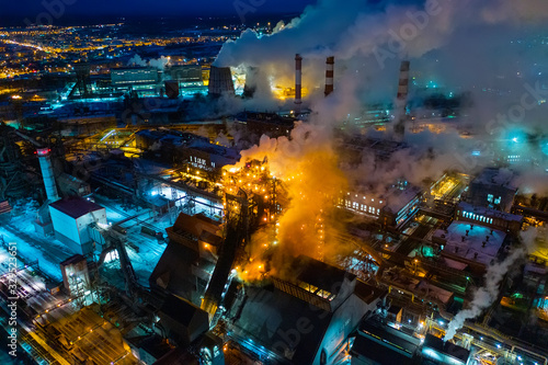 Night top view of a steel mill. Smog  smoke and flame from the chimneys. Metallurgical blast furnace in lights and smoke