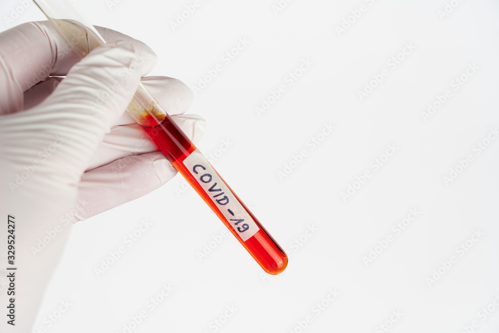 Naklejka premium Hand with a laboratory tube with blood sample and the imprint Covid-19