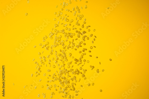 Freeze motion of flying uncooked pasta on yellow background  food concept