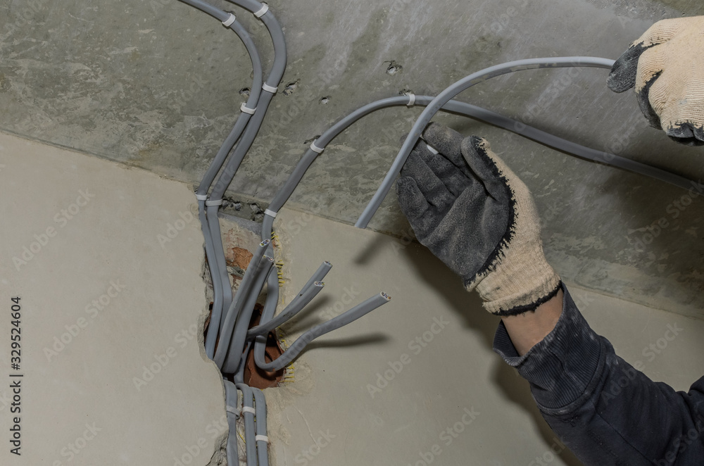 Work electrician installs new wiring in the wall