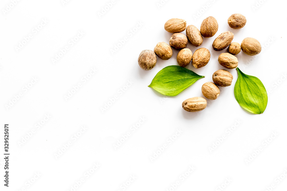 Nutmeg - whole nuts near leves - on white background top-down copy space Nutmeg - whole nuts near leves - on white background top-down copy space