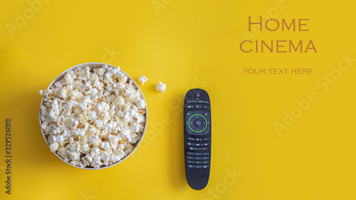 Foto Popcorn bowl and remote control on yellow background