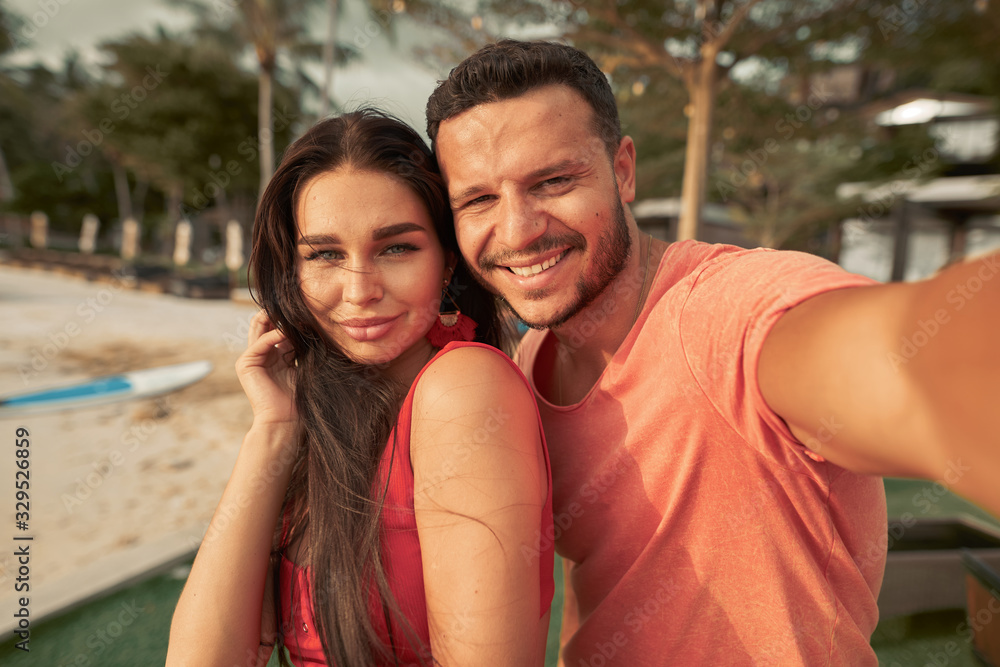 Handsome smiling couple having fun together taking a selfie photo at the beach bar