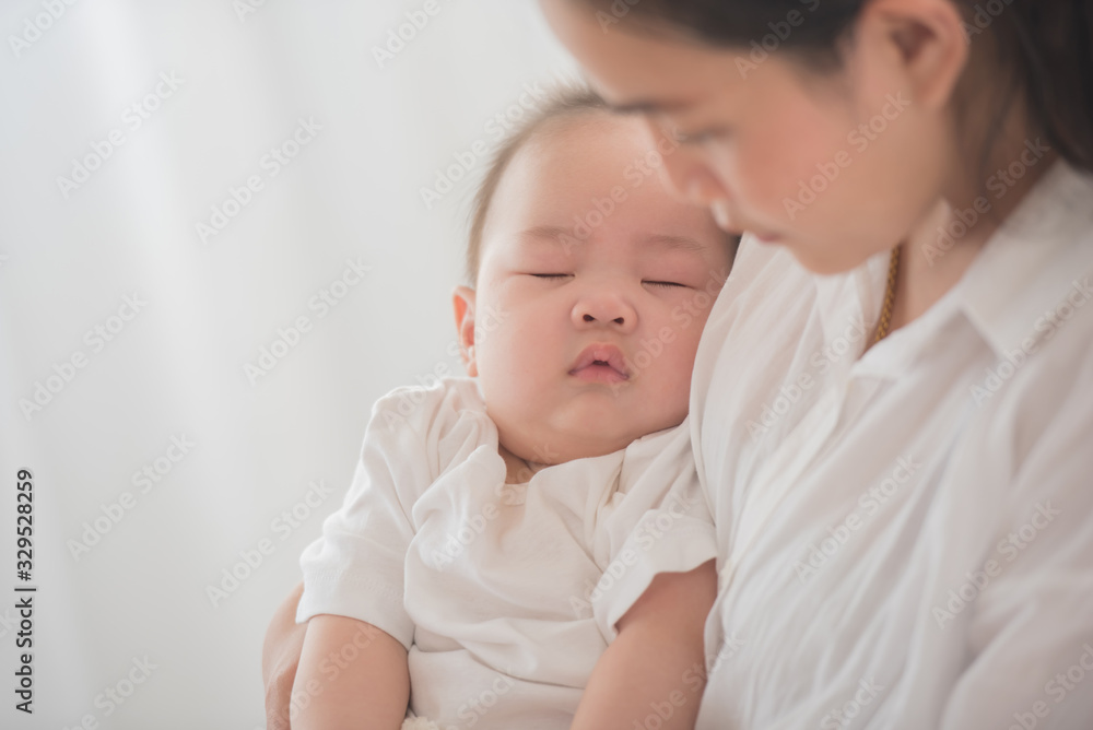 happy loving family. mother playing with her baby in the bedroom. asian mother hugging and holding her baby. family, motherhood, parenting, family and child care concept. White background. happy loving family. mother playing with her baby in the bedroom. asian mother hugging and holding her baby. family, motherhood, parenting, family and child care concept. White background.