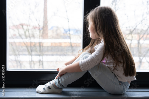 Adorable little girl sitting by the window. Free Download Adorable little girl sitting by the window. - GFXLoad