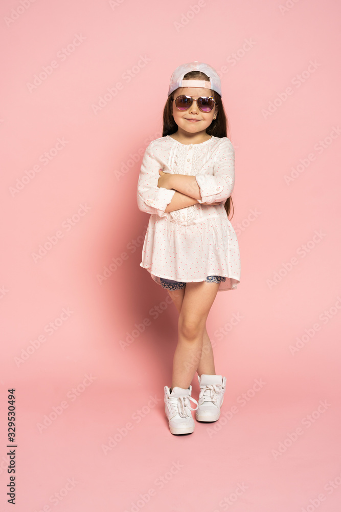 Laughing fashion little girl isolated on pink background.