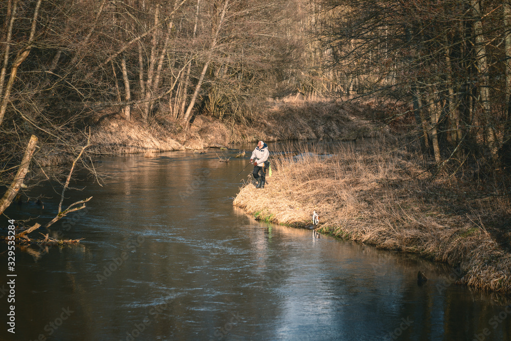 Fisherman and his dog on the river bank. Fisherman and his dog on the river bank.