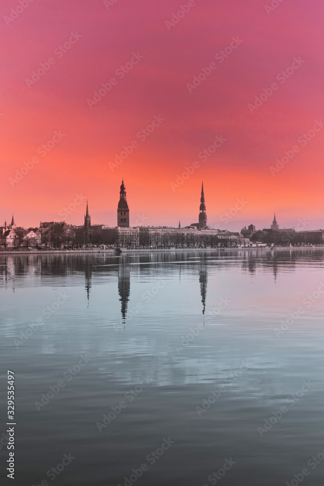 Cityscape of Riga Latvia with Reflections on a Quiet Still River at Sunset