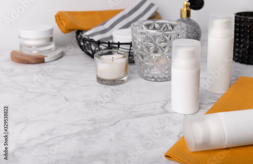 Cosmetic bottle containers with yellow towels and accessories on marble table