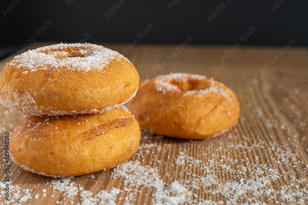 Top view of donuts on wooden board with sugar and black background in horizontal Top view of donuts on wooden board with sugar and black background in horizontal