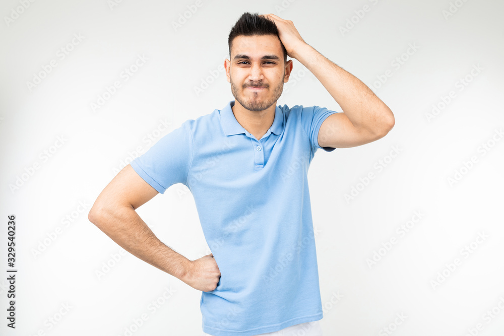 man in a blue T-shirt looking for a solution holding on to his head on a white studio background man in a blue T-shirt looking for a solution holding on to his head on a white studio background