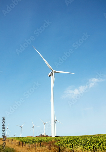 Windmills wind turbines farm power generators against landscape against blue sky in beautiful nature landscape for production of renewable green energy. Friendly industry to environment.