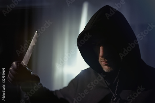 A man with a bloody knife standing in apartment, hands leather gloves, armed robbery, ruthless assassin  photo