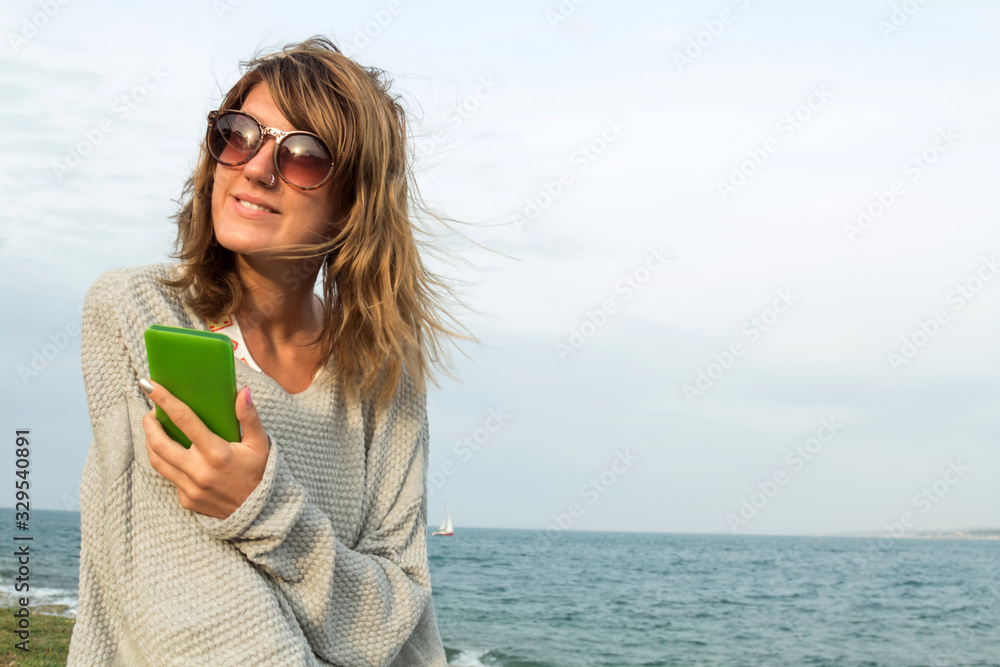 Young woman using cellphone on the beach.