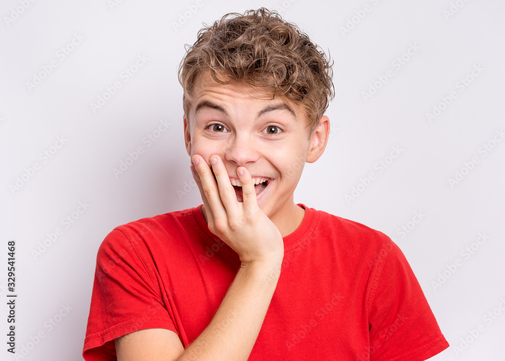 Portrait of surprised teen boy, on grey background. Funny child looking at camera in shock or amazement. Handsome caucasian young teenager has open from surprise of mouth. Portrait of surprised teen boy, on grey background. Funny child looking at camera in shock or amazement. Handsome caucasian young teenager has open from surprise of mouth.