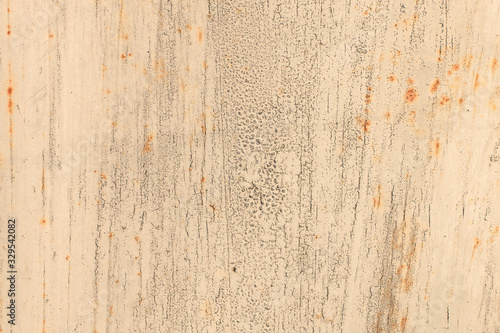 Old rusty metal wall covered with beige cracked peeling paint with spots of rust. Abstract modern trendy texture background