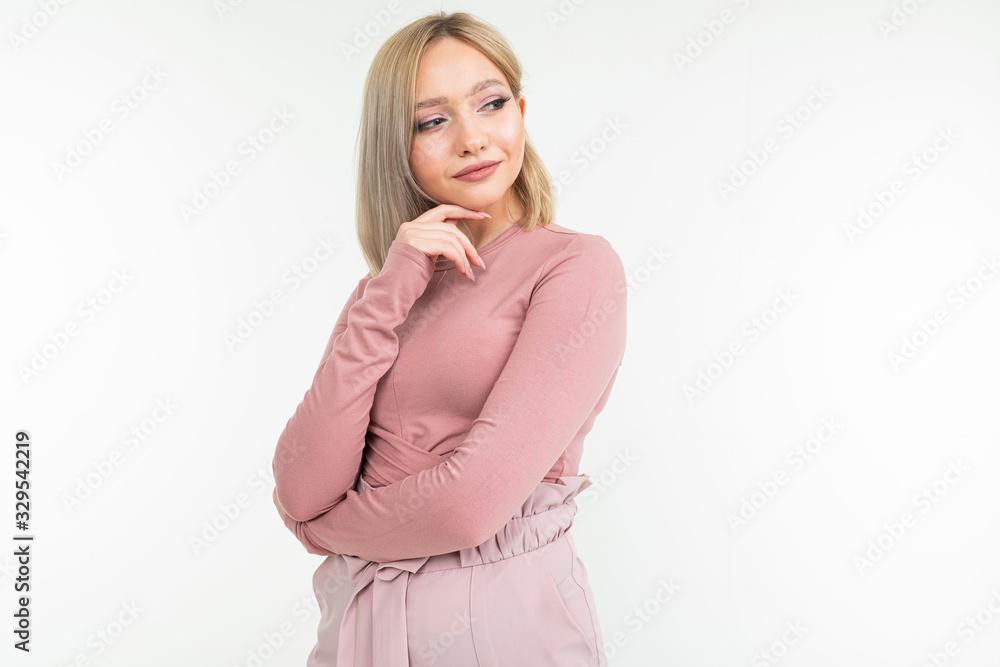 Cute blond girl with a short haircut mysteriously thinks on a white studio background with copy space Cute blond girl with a short haircut mysteriously thinks on a white studio background with copy space