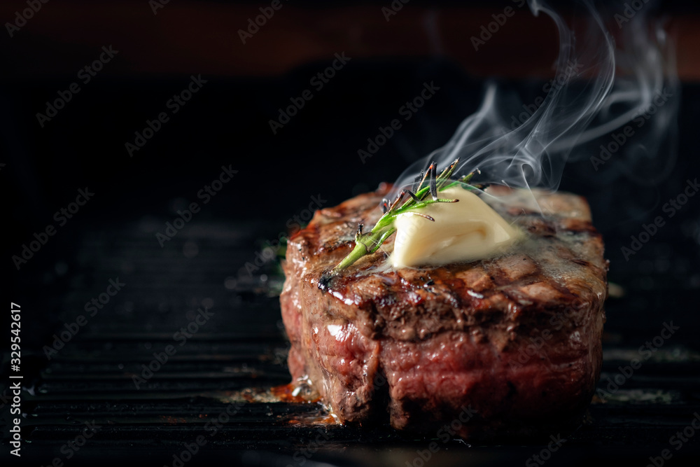 A steaming beef tenderloin steak is grilled in a grill pan with the text copy space. The concept of the recipe , filet Mignon - obrazy, fototapety, plakaty 