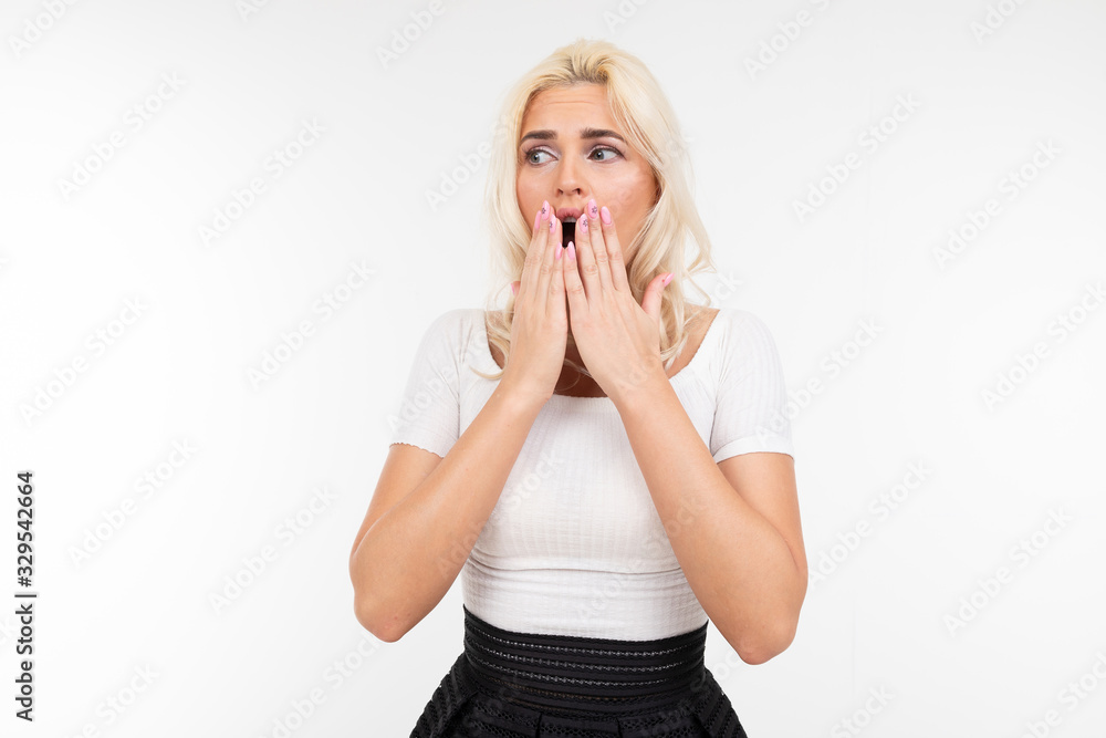 surprised blond woman covers her mouth on a white background with copy space surprised blond woman covers her mouth on a white background with copy space