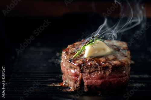A steaming beef tenderloin steak is grilled in a grill pan with the text copy space Fototapeta