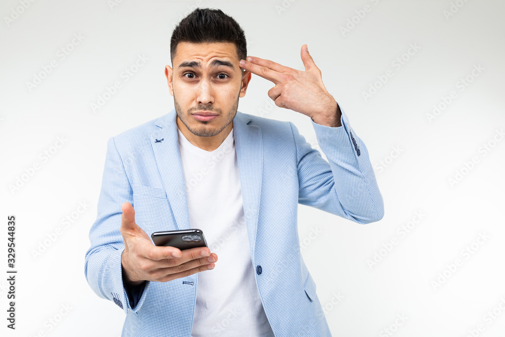 businessman twists at his temple and is surprised with information on the Internet holding a phone in red on a white background studio with copy space businessman twists at his temple and is surprised with information on the Internet holding a phone in red on a white background studio with copy space