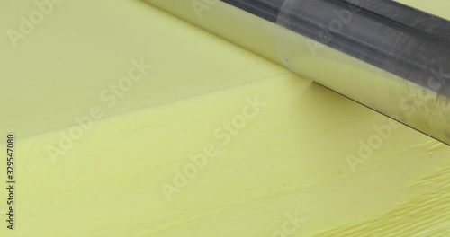 Close-up, a large yellow cube of foam passes through a wide sharp knife. production of soft products for domestic and industrial use. polyurethane foam lightweight material