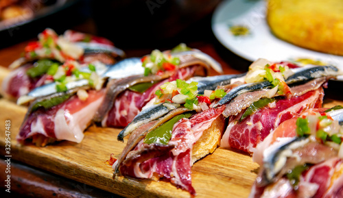 Print op canvas Appetizing spanish tapas with jamon, anchovies and green vegetables on wooden tr