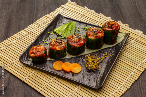 Korean style stuffed cucumbers. Kojori kimchi spicy snack. Fermented and marinated vegetables. Wooden background photo