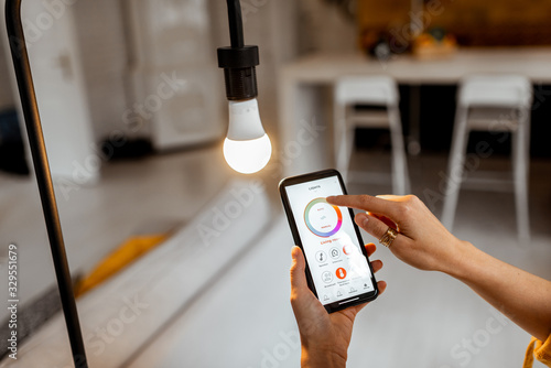 Controlling light bulb temperature and intensity with a smartphone application. Concept of a smart home and managing light with mobile devices photo