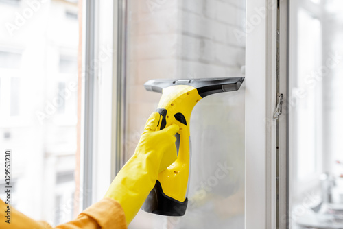 Woman washing windows with a special cleansing device at home, close-up on eqipment. Concept of a professional housekeeping photo