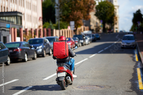 Photography Delivery service from cafes and restaurants, delivery boy on scooter with red backpack driving fast