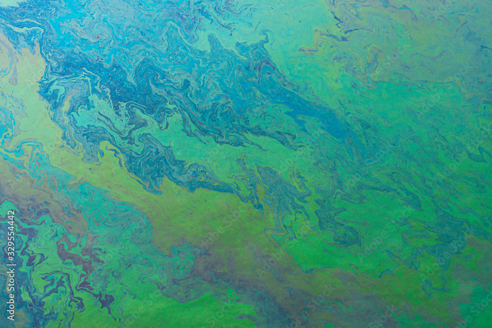Blue, green, yellow color oil patterns on the surface of the water Blue, green, yellow color oil patterns on the surface of the water